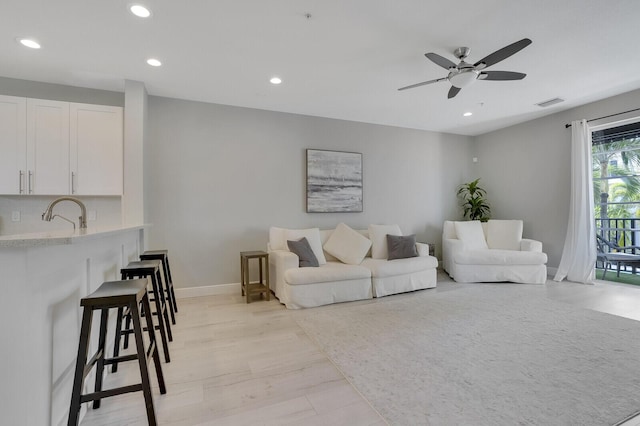 living room featuring light hardwood / wood-style floors, ceiling fan, and sink