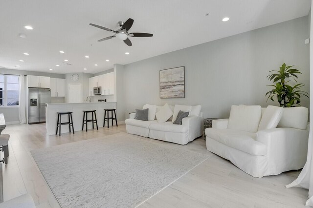 living room with ceiling fan, light hardwood / wood-style floors, and sink