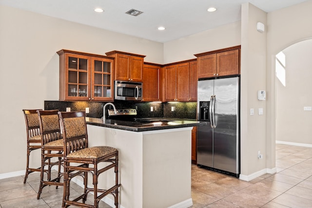 kitchen with tasteful backsplash, a kitchen bar, visible vents, and stainless steel appliances