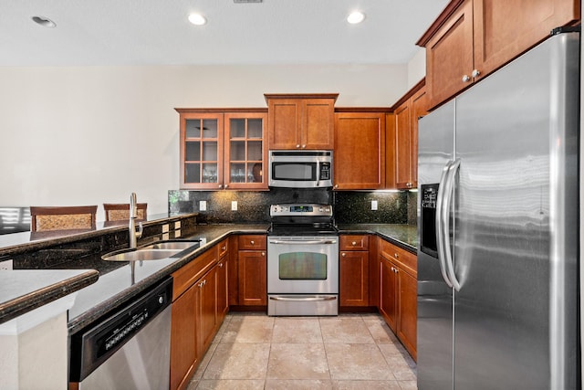 kitchen featuring backsplash, appliances with stainless steel finishes, brown cabinets, and a sink