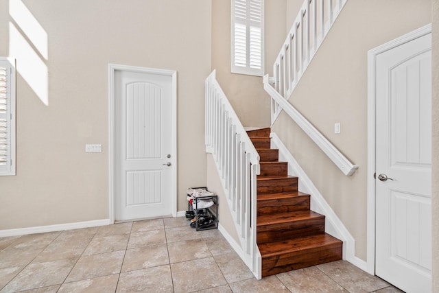 entryway featuring light tile patterned flooring, a towering ceiling, and baseboards