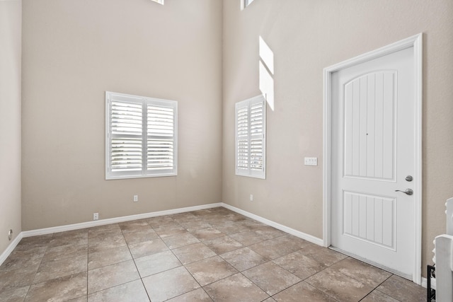 interior space featuring a towering ceiling, baseboards, and light tile patterned floors