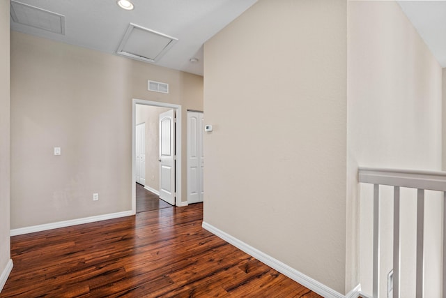 empty room with attic access, baseboards, visible vents, and dark wood-type flooring