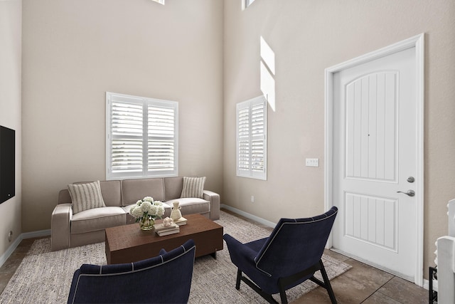 living room featuring a high ceiling, baseboards, and tile patterned floors