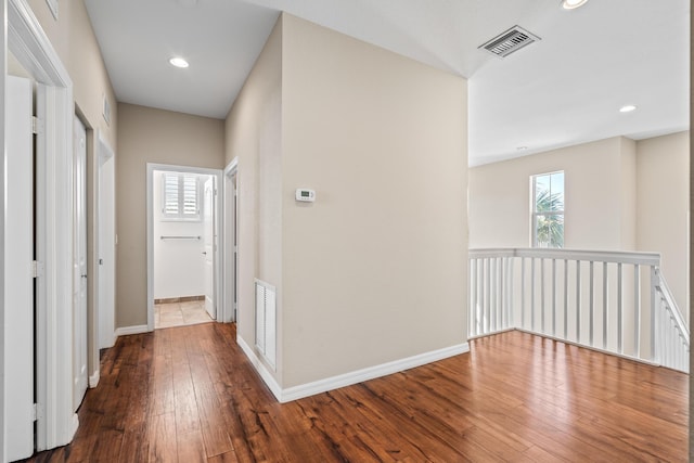 corridor with baseboards, visible vents, hardwood / wood-style floors, and recessed lighting