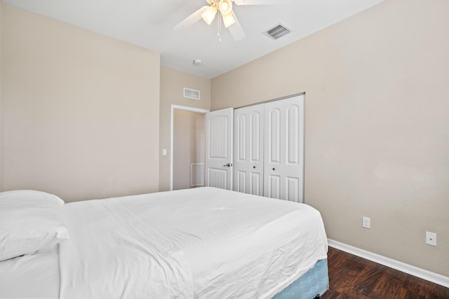 bedroom with dark wood-style floors, baseboards, visible vents, and a closet