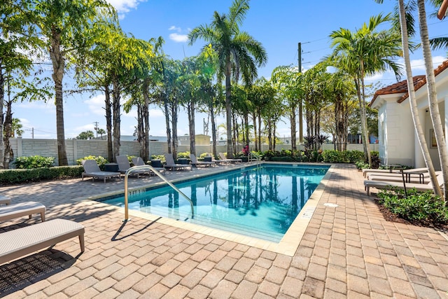 community pool featuring fence and a patio