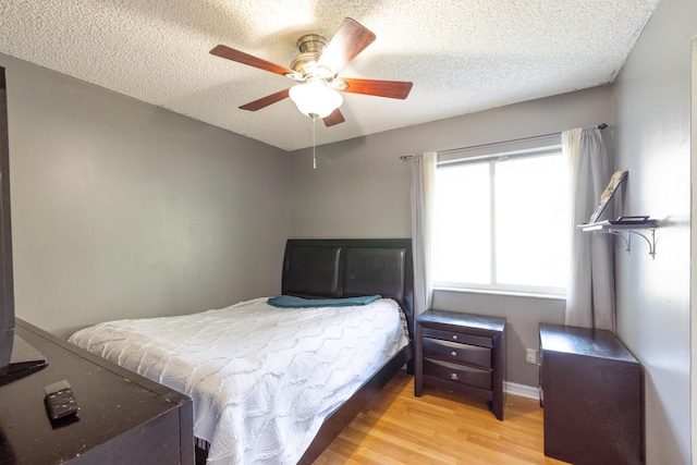 bedroom with a textured ceiling, light hardwood / wood-style flooring, and ceiling fan