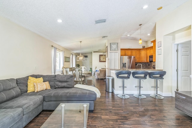 living room featuring dark hardwood / wood-style flooring, a textured ceiling, lofted ceiling, and sink