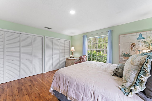 bedroom featuring multiple closets and hardwood / wood-style flooring