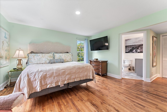 bedroom with ensuite bathroom and wood-type flooring