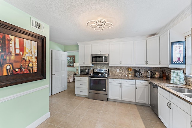 kitchen featuring light tile patterned flooring, tasteful backsplash, white cabinetry, dark stone counters, and stainless steel appliances