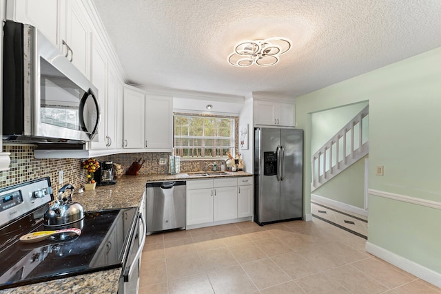 kitchen featuring white cabinetry, tasteful backsplash, a textured ceiling, appliances with stainless steel finishes, and dark stone counters