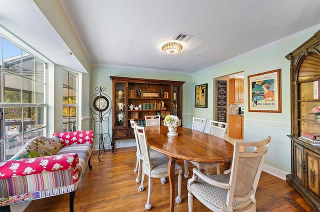 dining space with crown molding, wood-type flooring, and a textured ceiling