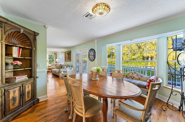 dining room featuring dark hardwood / wood-style flooring, a wealth of natural light, ornamental molding, and a textured ceiling