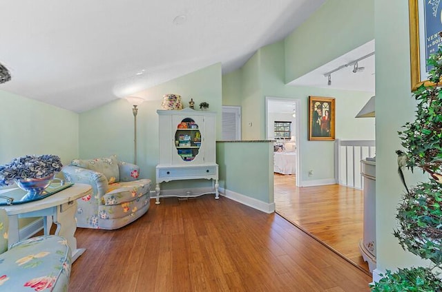 sitting room with hardwood / wood-style flooring, vaulted ceiling, and track lighting