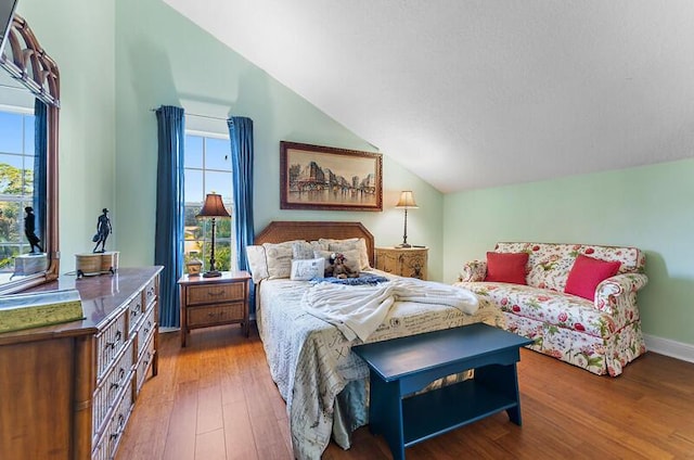 bedroom featuring multiple windows, wood-type flooring, and vaulted ceiling