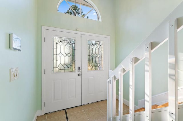 foyer entrance with light tile patterned floors and a towering ceiling