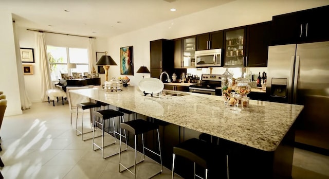 kitchen featuring a spacious island, a breakfast bar, light tile patterned flooring, and stainless steel appliances