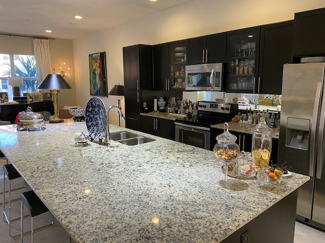 kitchen featuring light stone countertops, sink, stainless steel appliances, and a large island