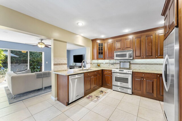 kitchen with dishwasher, sink, light stone counters, and ceiling fan with notable chandelier