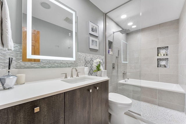 full bathroom featuring vanity, tiled shower / bath combo, and toilet