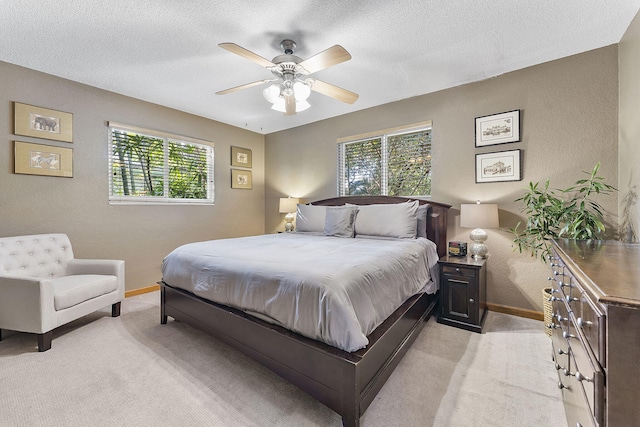 bedroom featuring a textured wall, baseboards, a textured ceiling, and light colored carpet