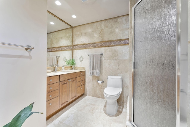 bathroom featuring vanity, toilet, a shower with shower door, and tile walls