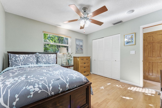 bedroom with hardwood / wood-style flooring, ceiling fan, a textured ceiling, and a closet