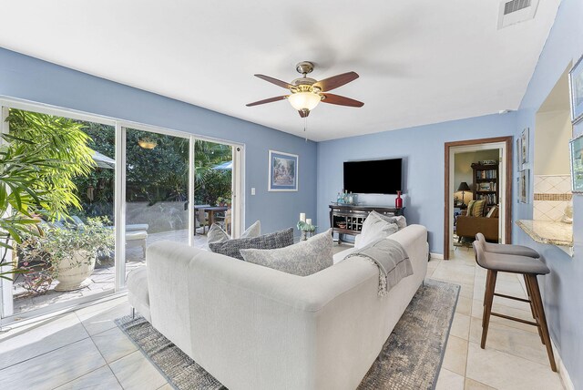 living room with a textured ceiling, ceiling fan, light tile patterned flooring, and crown molding