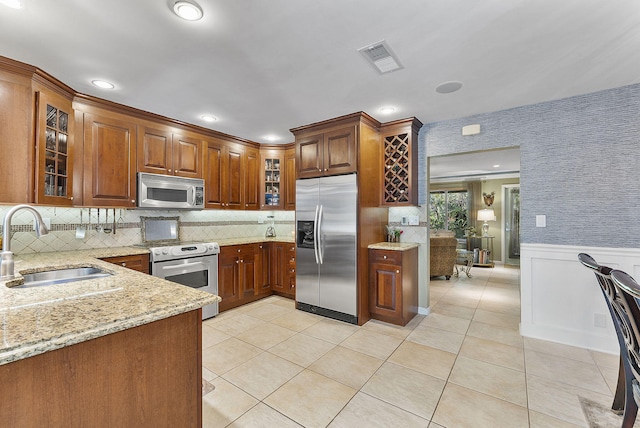 kitchen featuring light stone counters, light tile patterned floors, sink, and appliances with stainless steel finishes