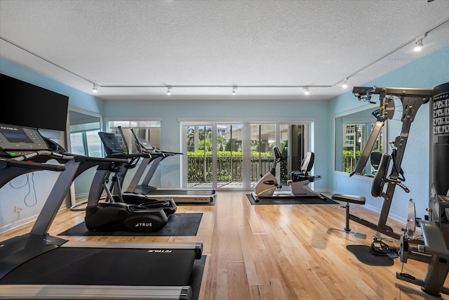 workout area featuring a textured ceiling and light wood-type flooring