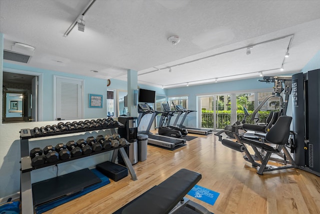 workout area featuring hardwood / wood-style floors, a textured ceiling, and track lighting