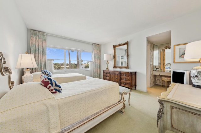 bedroom featuring ensuite bath and light colored carpet