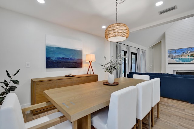 dining area with vaulted ceiling with beams and light hardwood / wood-style flooring