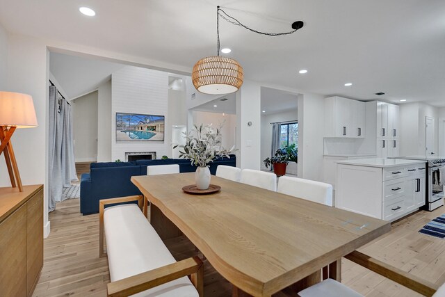 dining space featuring lofted ceiling, a fireplace, and light hardwood / wood-style floors