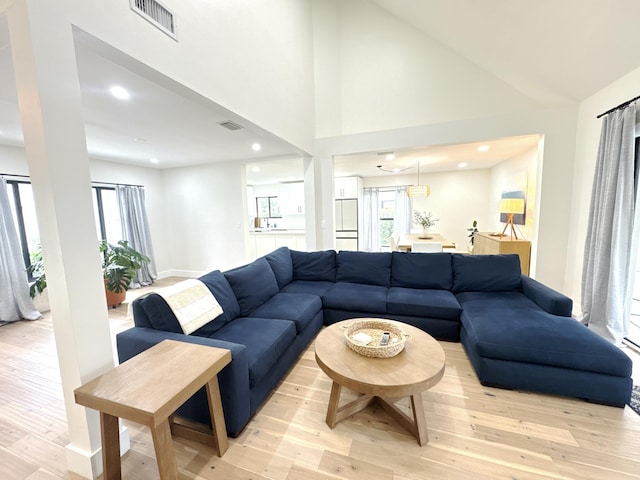 living room featuring high vaulted ceiling and light hardwood / wood-style flooring