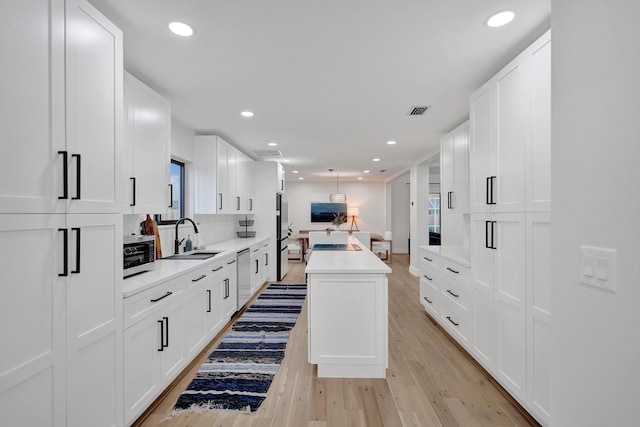 kitchen with appliances with stainless steel finishes, a center island, sink, and white cabinets