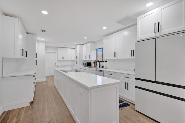 kitchen featuring a kitchen island, white cabinetry, appliances with stainless steel finishes, and light wood-type flooring