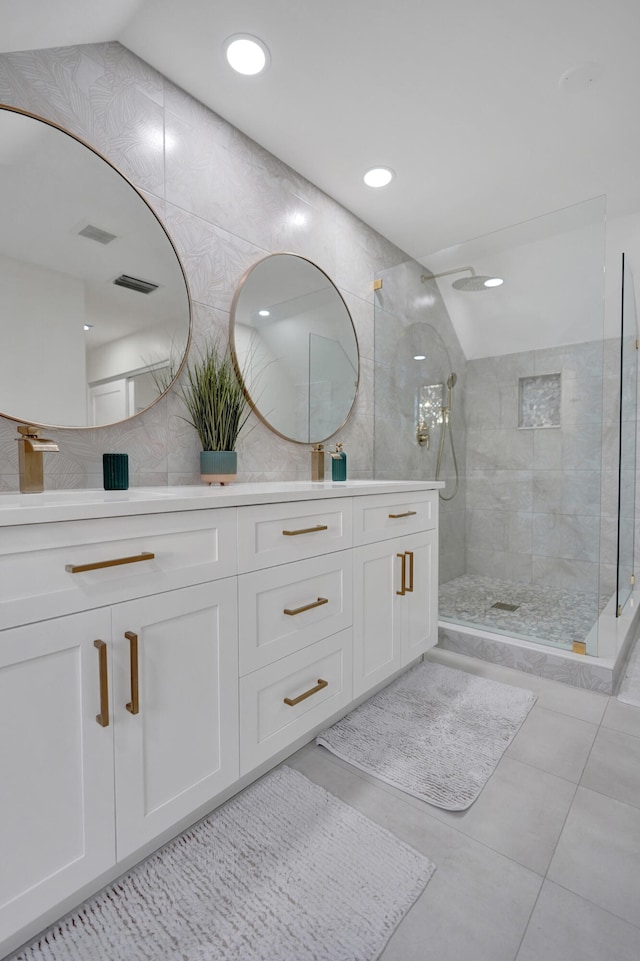 bathroom featuring a tile shower, vanity, and tile patterned flooring