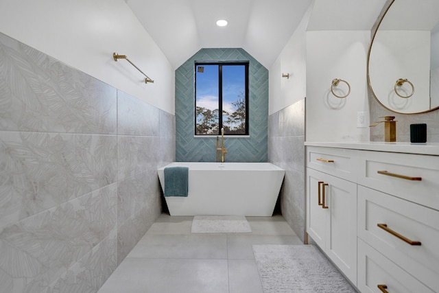 bathroom featuring lofted ceiling, tile walls, vanity, a bath, and tile patterned floors