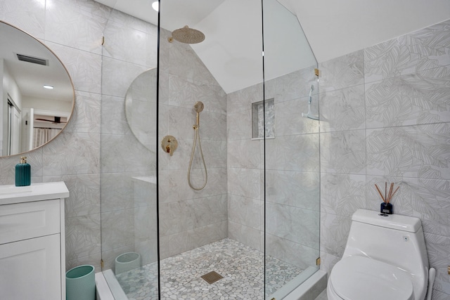 bathroom featuring lofted ceiling, toilet, tile walls, a tile shower, and vanity