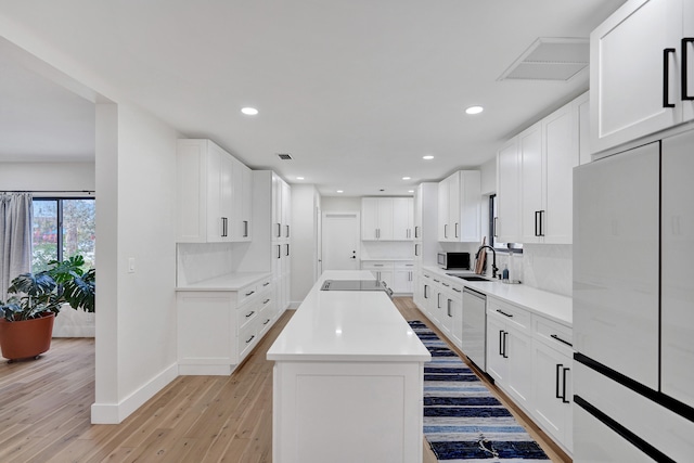 kitchen with white cabinetry, decorative backsplash, light hardwood / wood-style floors, and a kitchen island