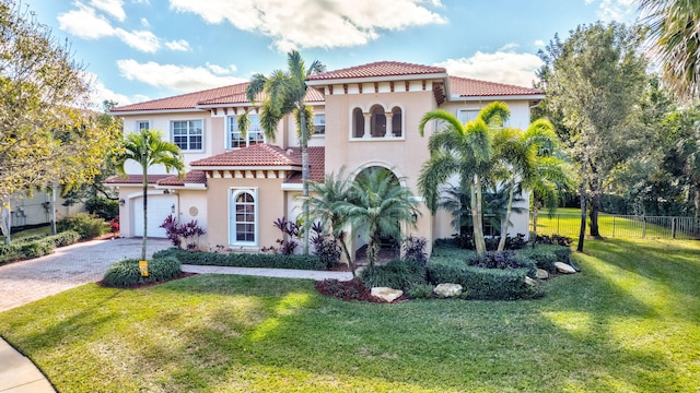 mediterranean / spanish house with a garage and a front lawn