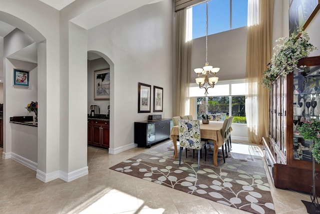 tiled dining area featuring a high ceiling and an inviting chandelier