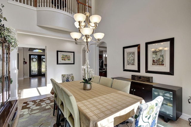 dining space with a towering ceiling, french doors, and a chandelier