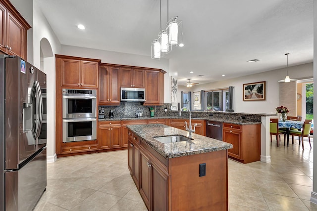 kitchen featuring appliances with stainless steel finishes, kitchen peninsula, hanging light fixtures, and a center island with sink