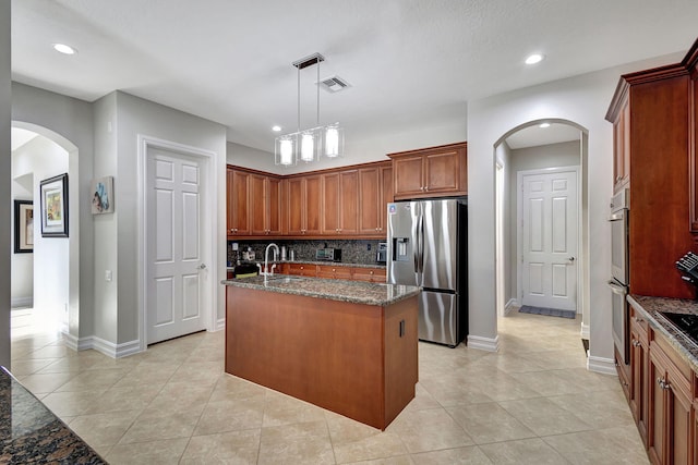 kitchen featuring sink, an island with sink, pendant lighting, stainless steel appliances, and backsplash