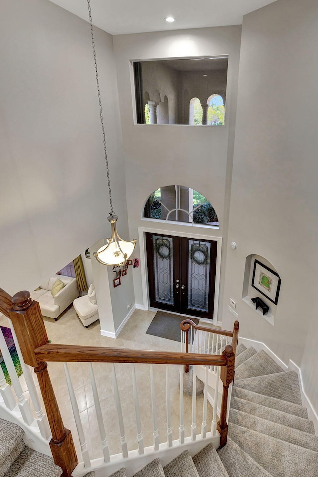 carpeted foyer featuring a towering ceiling and french doors