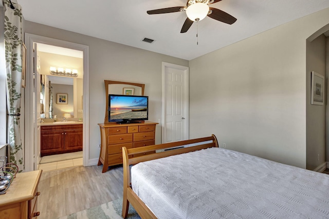 bedroom featuring connected bathroom, light hardwood / wood-style flooring, sink, and ceiling fan